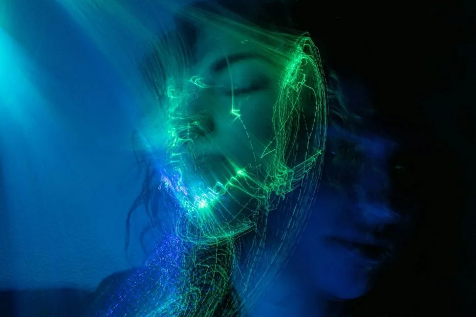 A person with eyes closed surrounded by swirling green and blue light trails